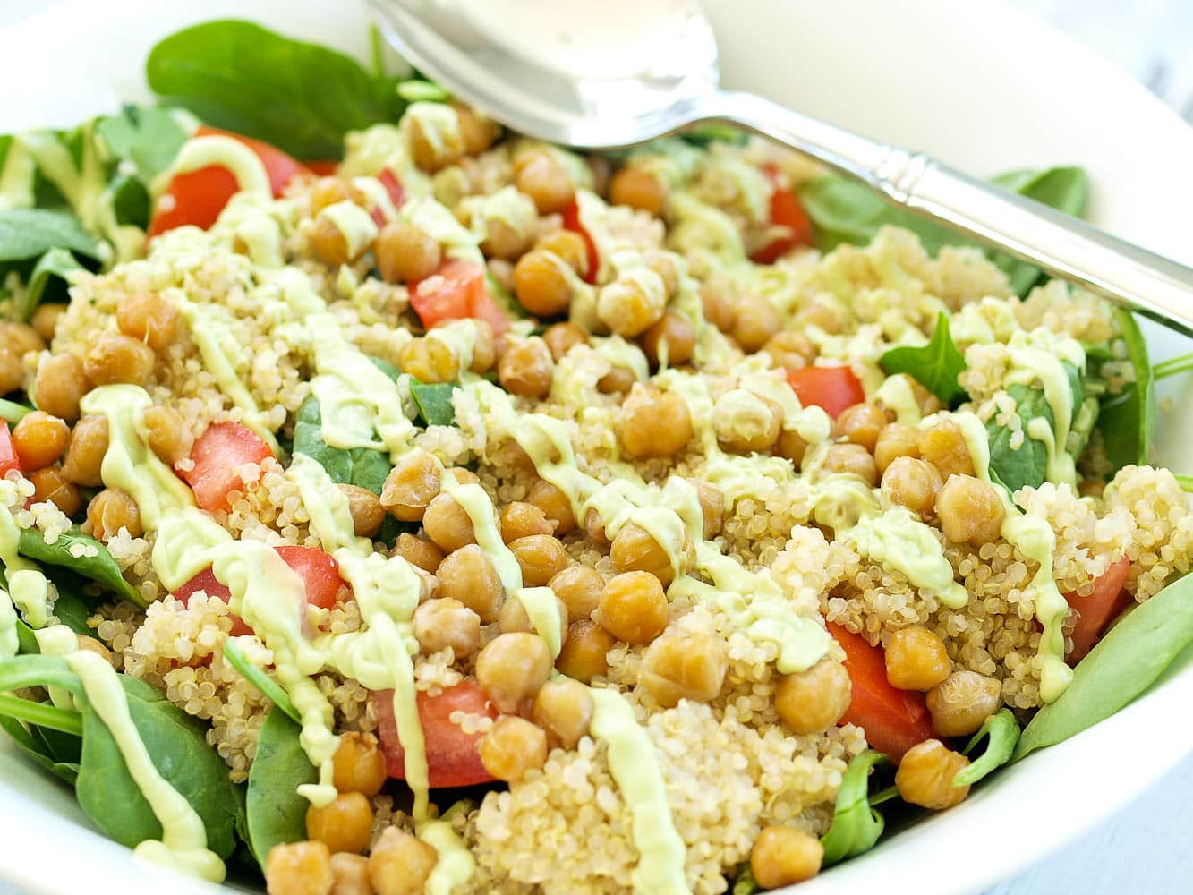 Spinach Salad with Quinoa, Crispy Chickpeas, Tomato, and Avocado Basil Dressing. A hearty, filling salad that can be a meal in itself! Easy healthy vegan recipe.