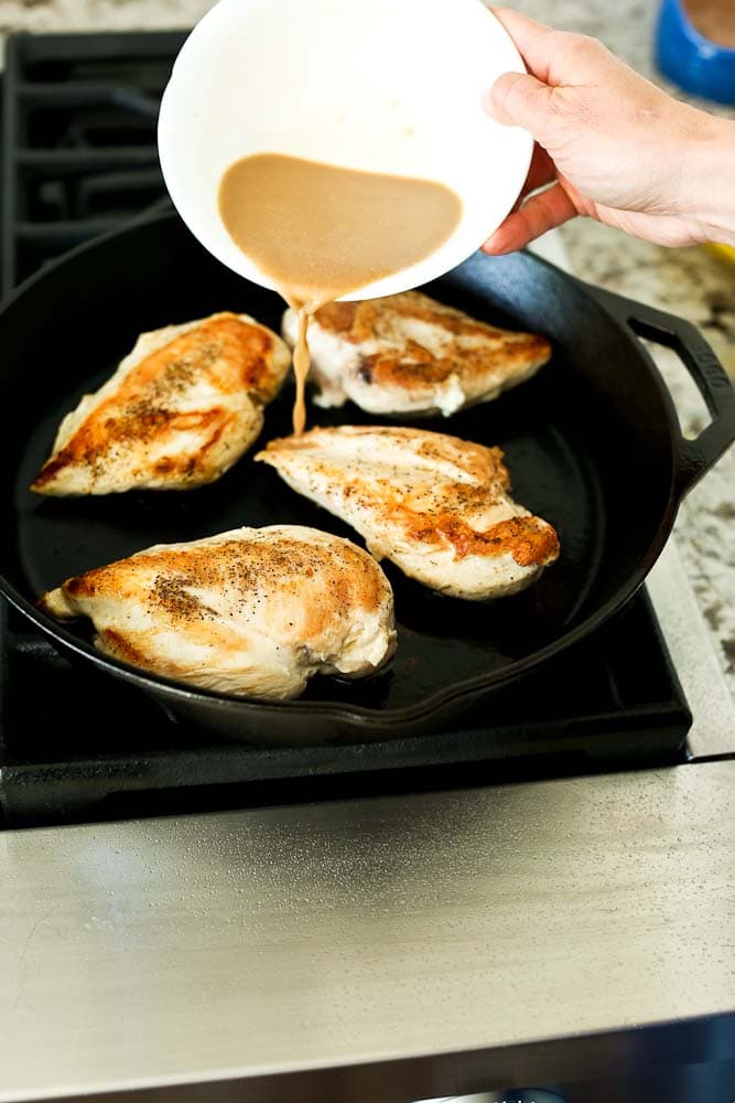 Adding liquid to the cast iron skillet with chicken breasts
