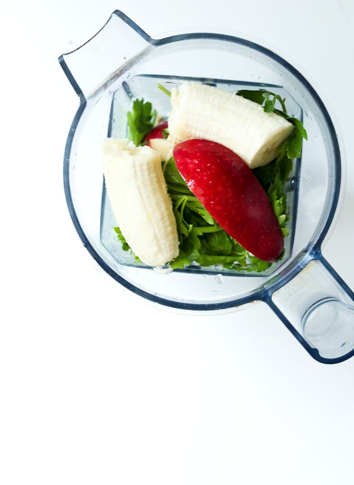 top of blender Ingredients for the Wake Me Up Green Smoothie Recipe (parsley, lime, apple, spinach cube)