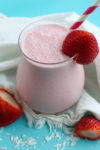 Strawberry Smoothie in a glass with strawberry on the rim and a pink and white straw
