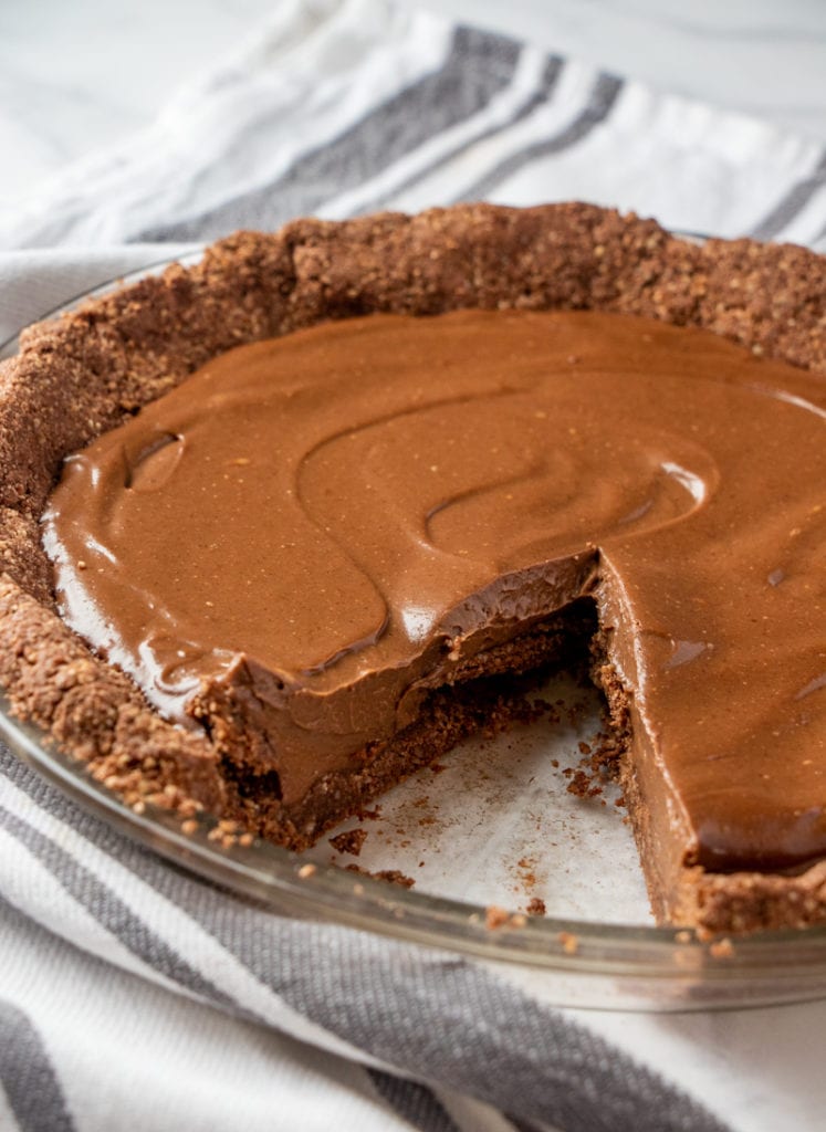 a whole vegan chocolate pie with a piece removed