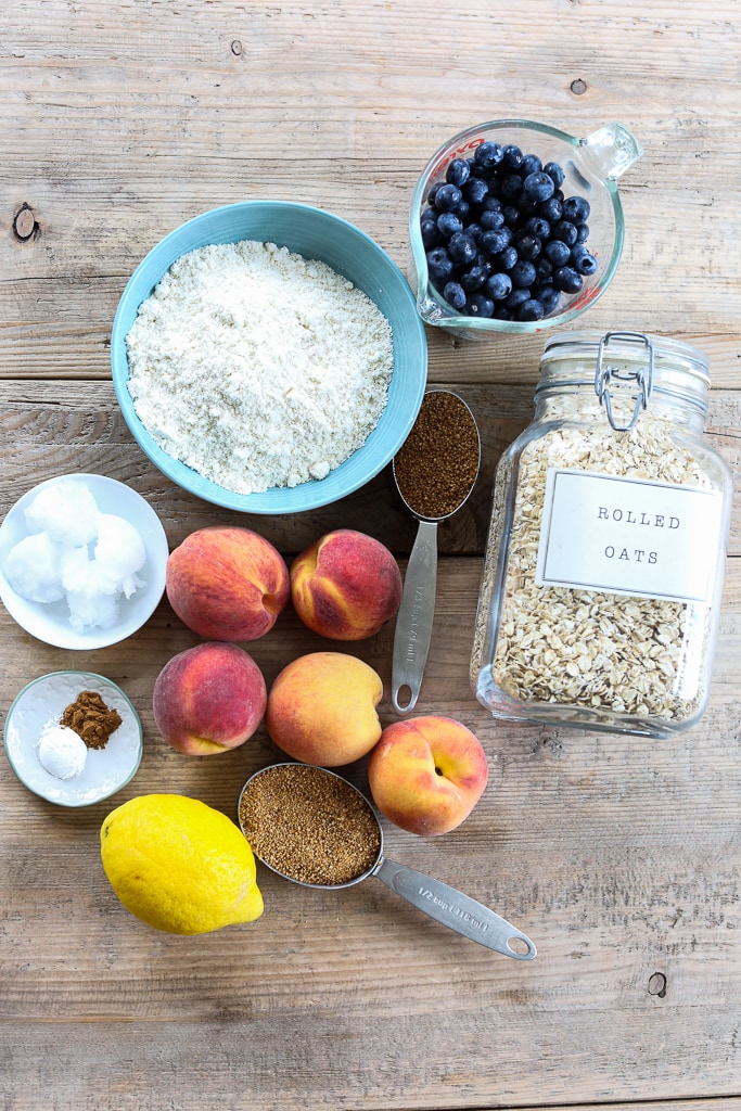 overhead shot of ingredients for healthy crisp recipe. Peaches blueberries flour oatmeal lemon coconut oil sugar