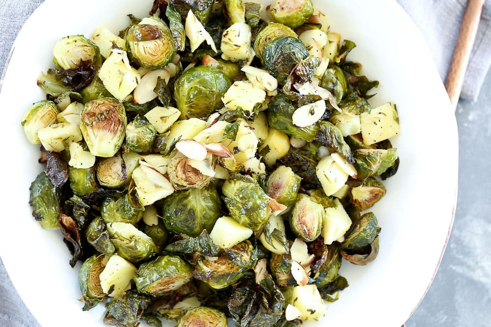 full shot of Roasted Brussels sprouts with apples and almonds in a white bowl recipe