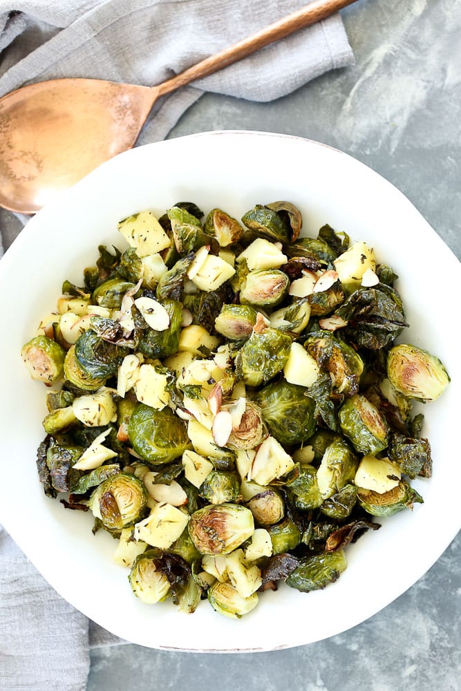 Roasted Brussels Sprouts with Apples and Almonds recipe with a copper serving spoon