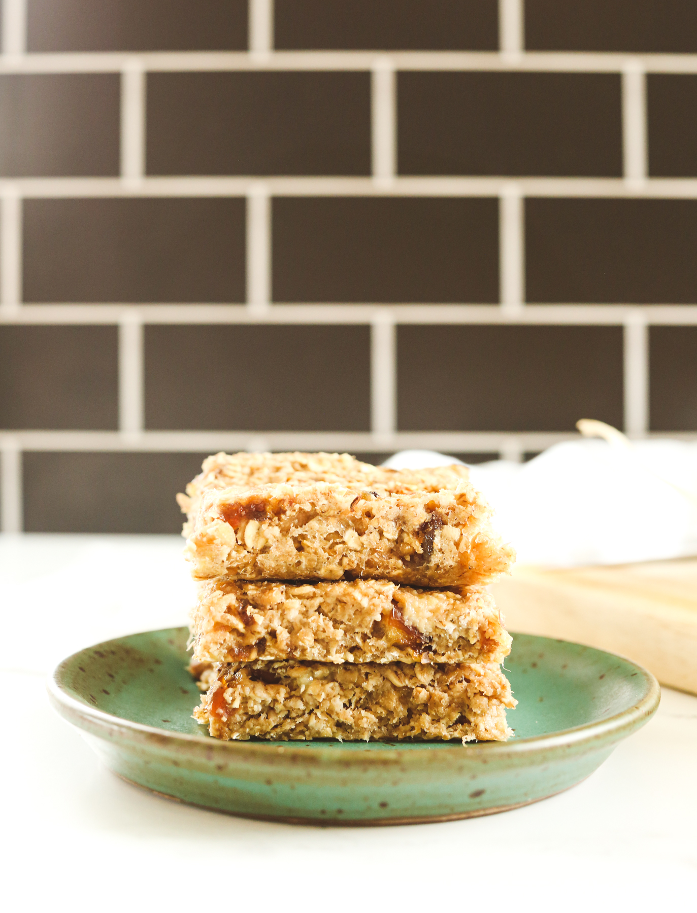 stack of 3 banana oatmeal bars on a green plate with a black background