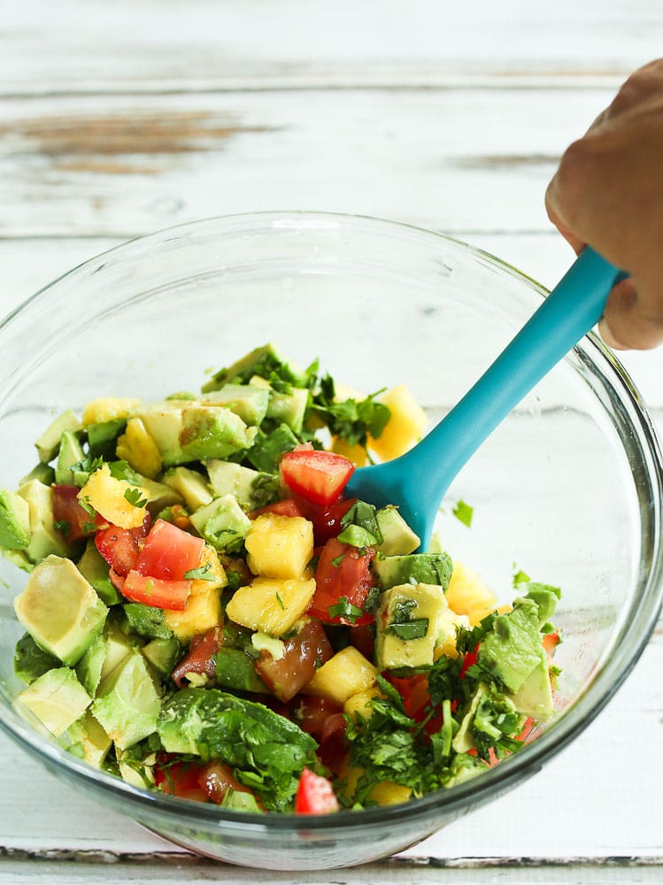 ingredients for pineapple avocado salsa in a bowl with a spoon