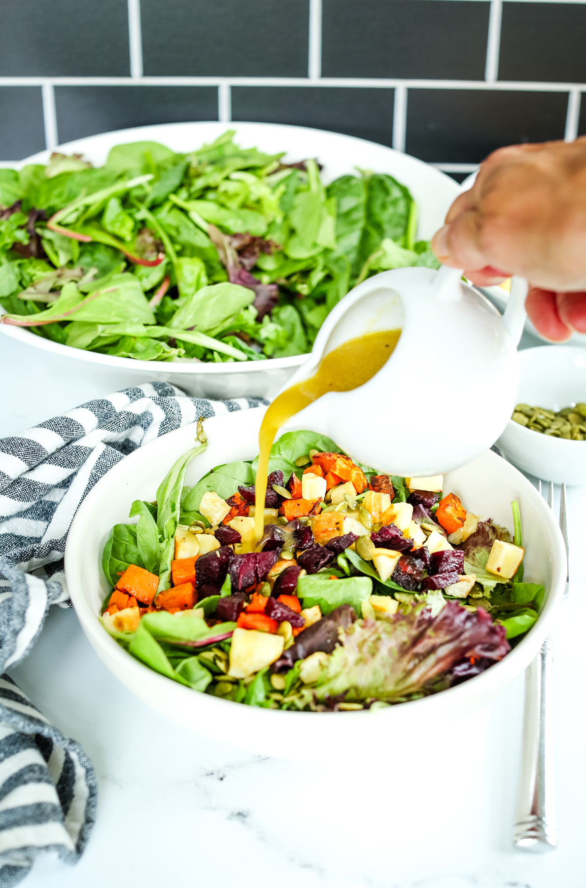 pouring dressing over roasted vegetable salad