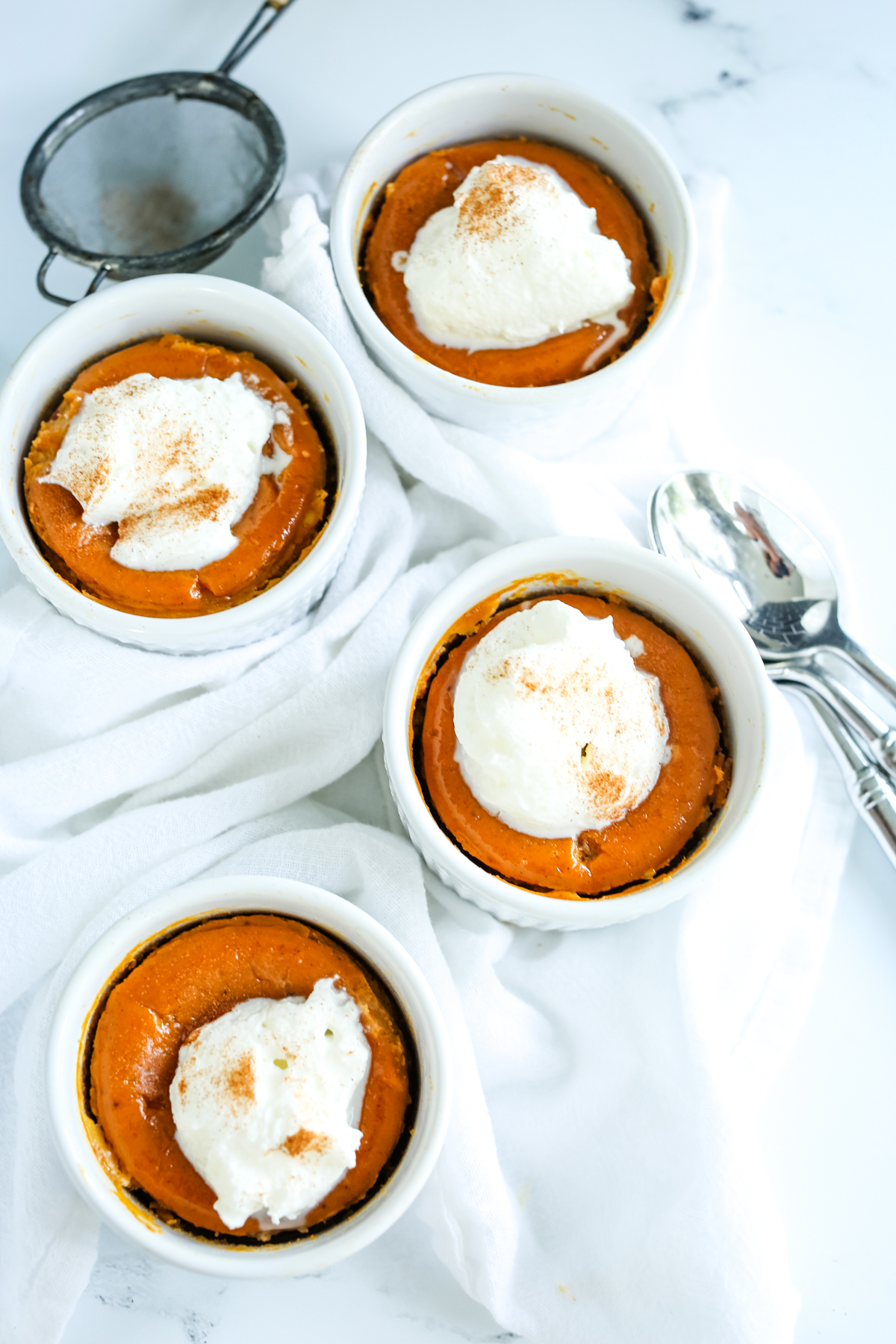 sweet potato pudding in ramekins with whipped cream on top