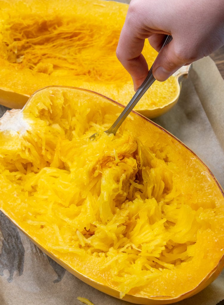 a fork scraping out the flesh of a cooked spaghetti squash
