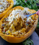 a cooked spaghetti squash with cheese and filling and a fork pulling out a bite