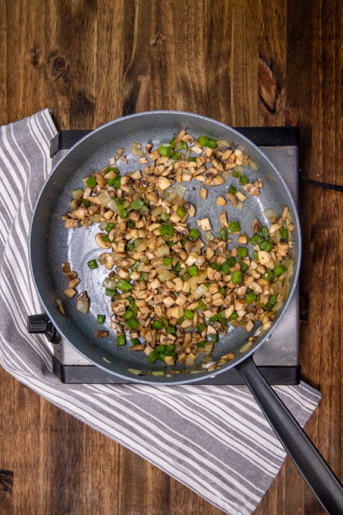 a pan with cooked mushrooms and green peppers and onions