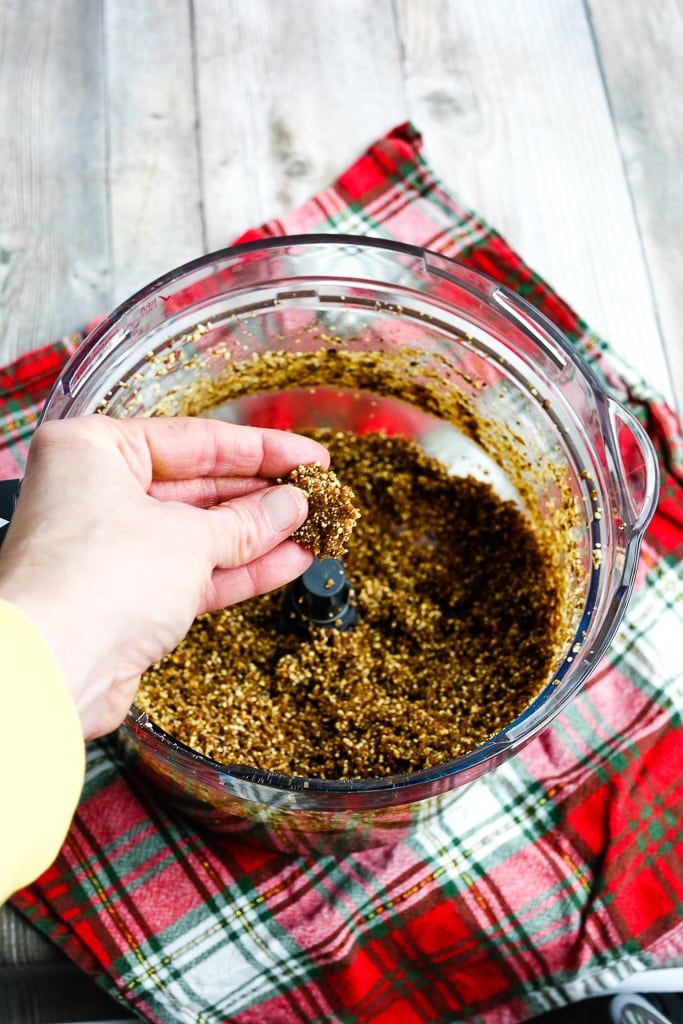 a hand holding the ingredients from the bowl of a food processor