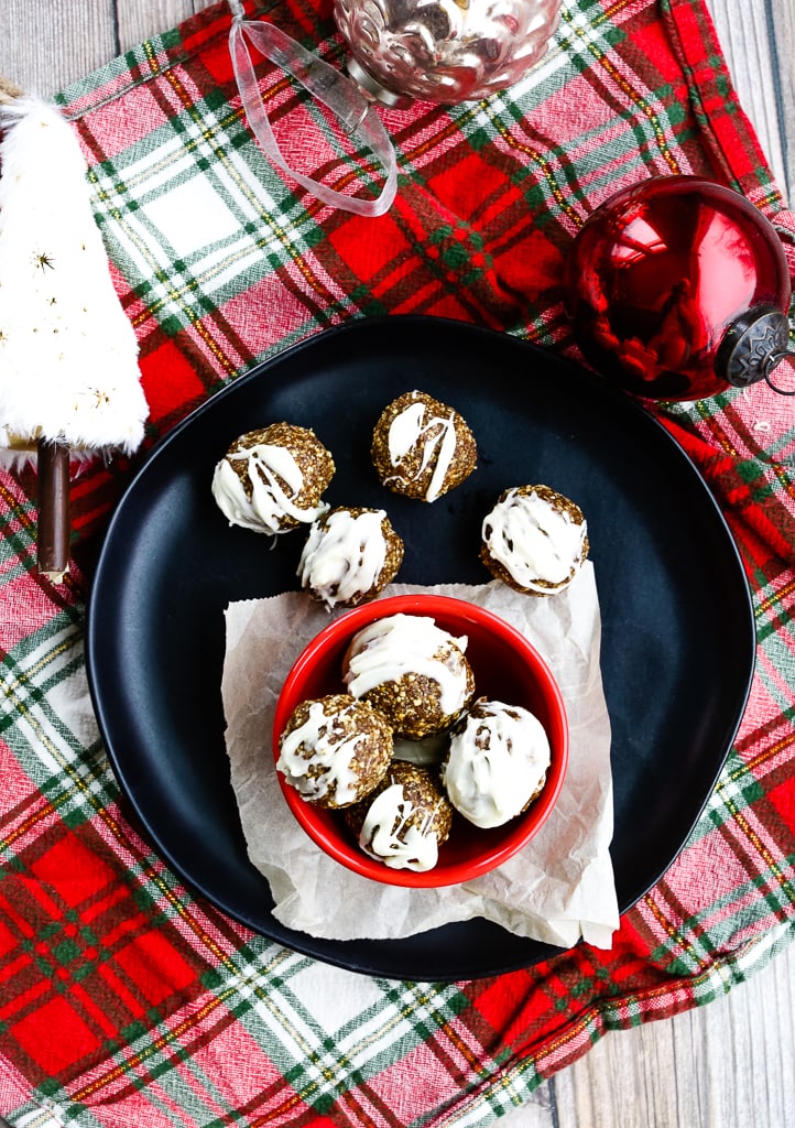an overhead shot of no bake gingerbread cookie energy balls on a plaid napkin, black plate, and christmas ornaments