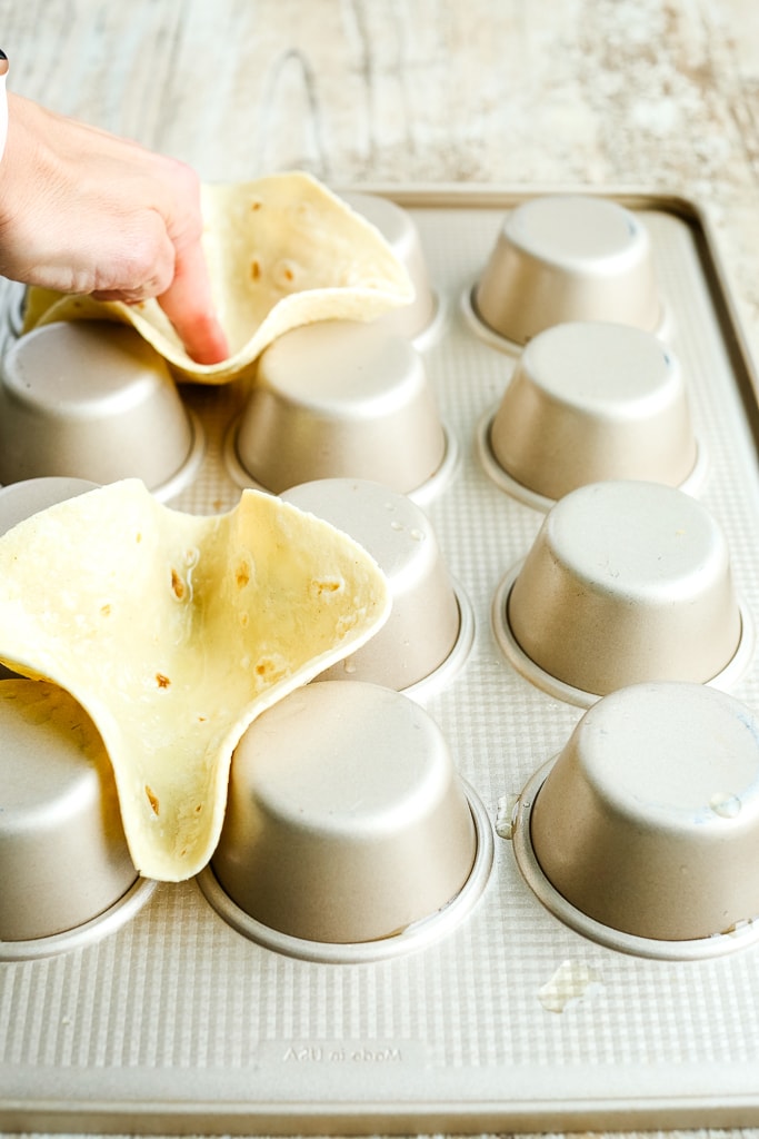 using an upside down muffin tin to make taco bowls with a tortilla shell