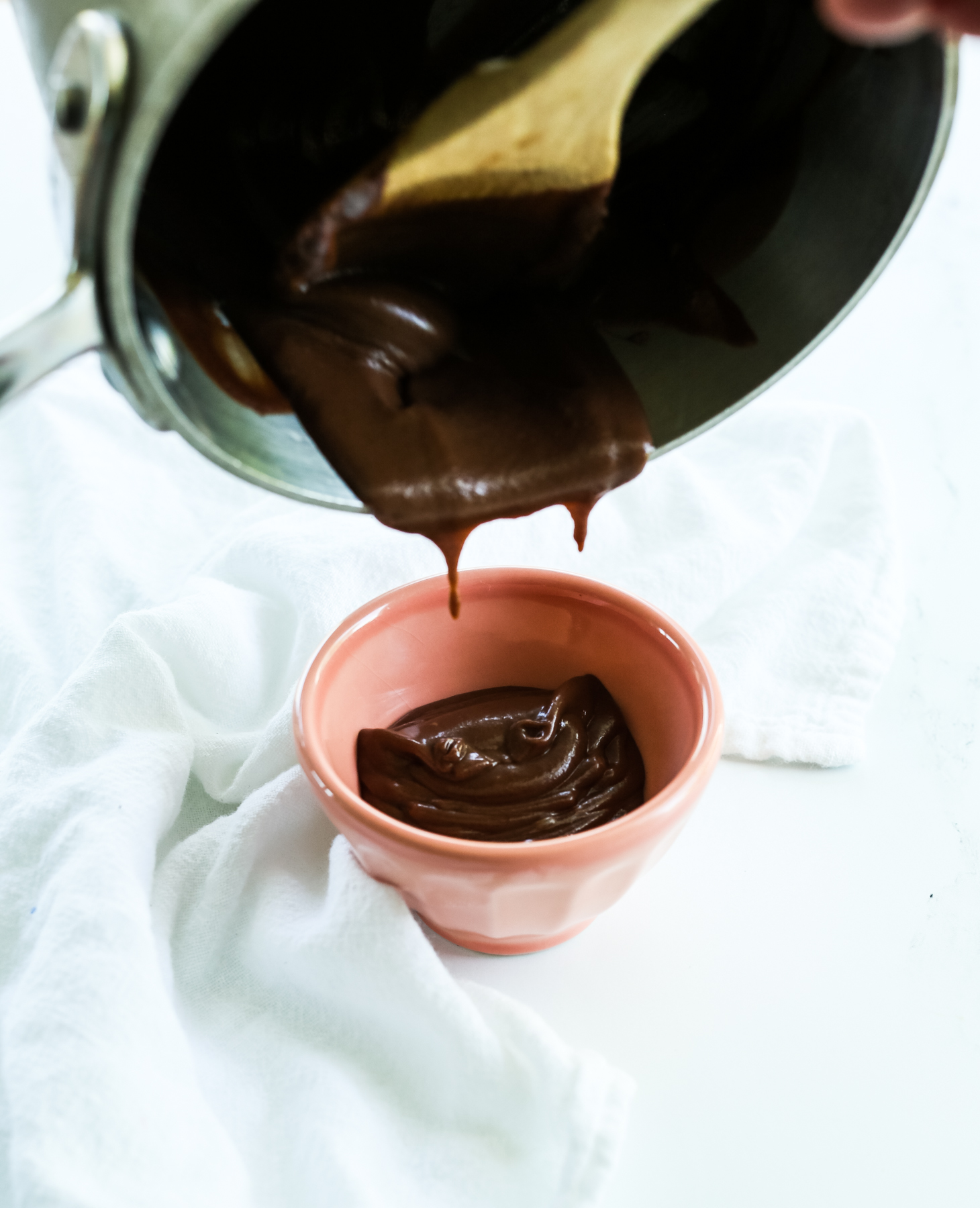 transferring hot fudge to a small bowl from saucepan