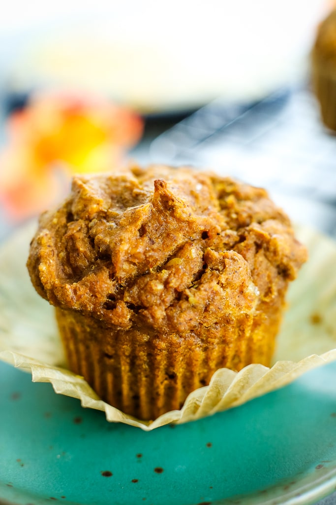 healthy pumpkin muffin on a green plate with a paper wrapper