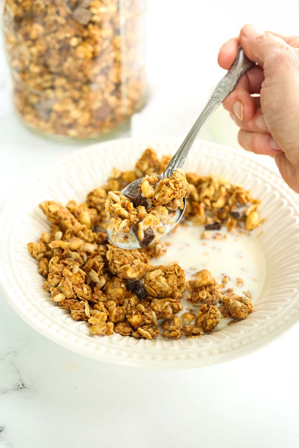 a bowl of peanut butter granola with the spoon lifting a bite