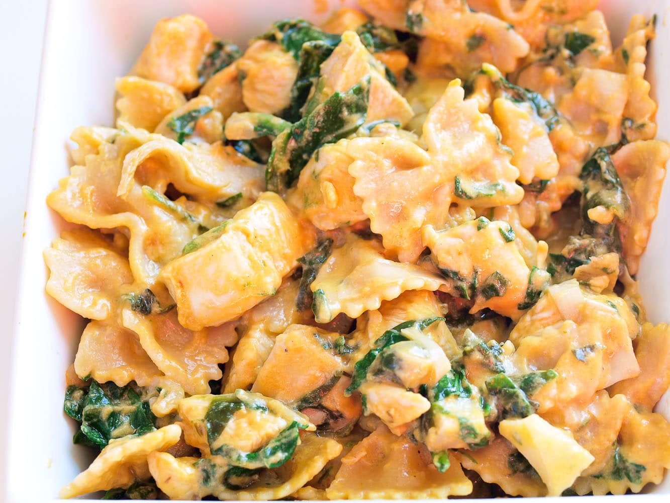 a close up shot of spinach artichoke pasta with chicken