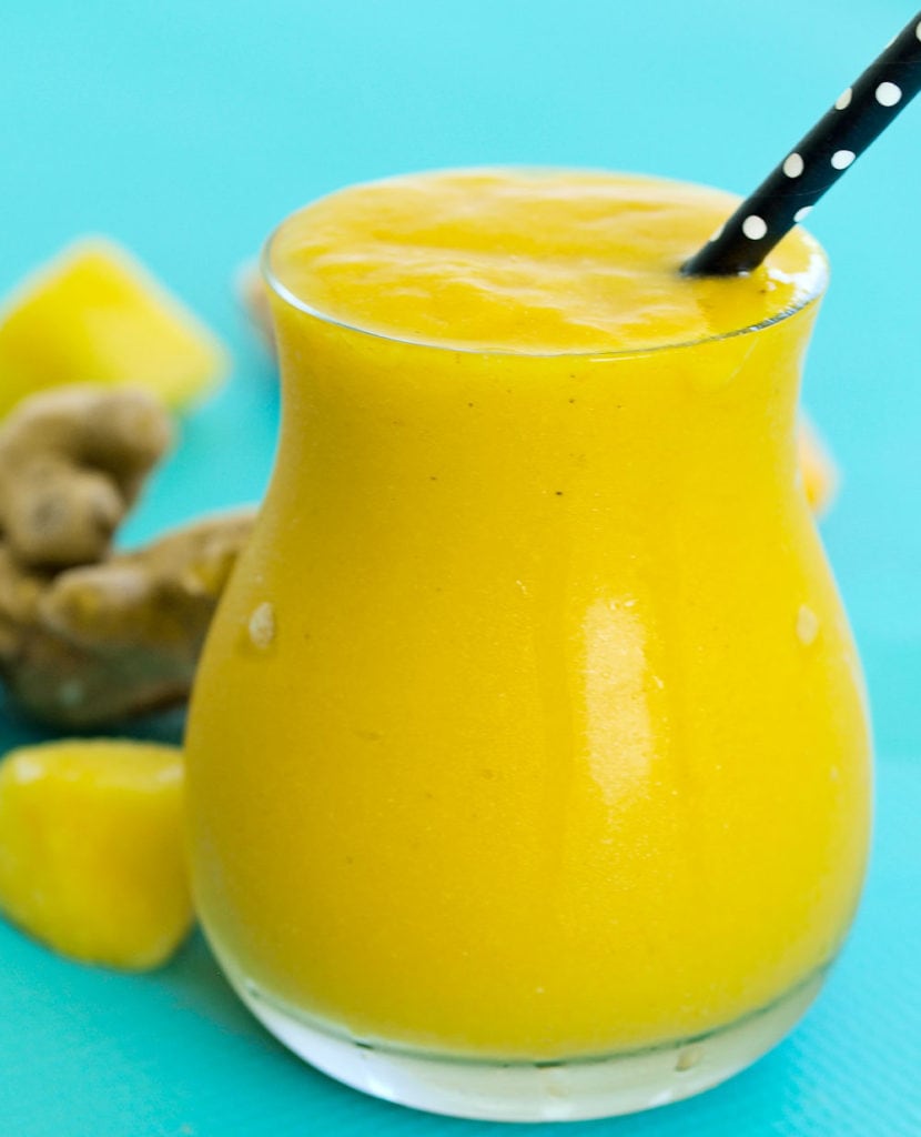 Close up of a golden smoothie in a glass with a black straw 