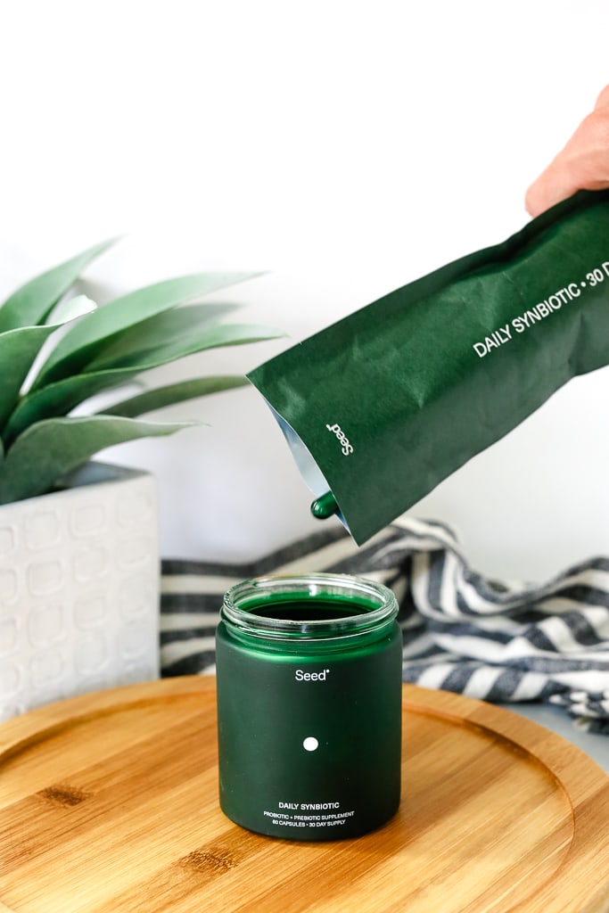 a hand refilling a bottle with probiotic capsules