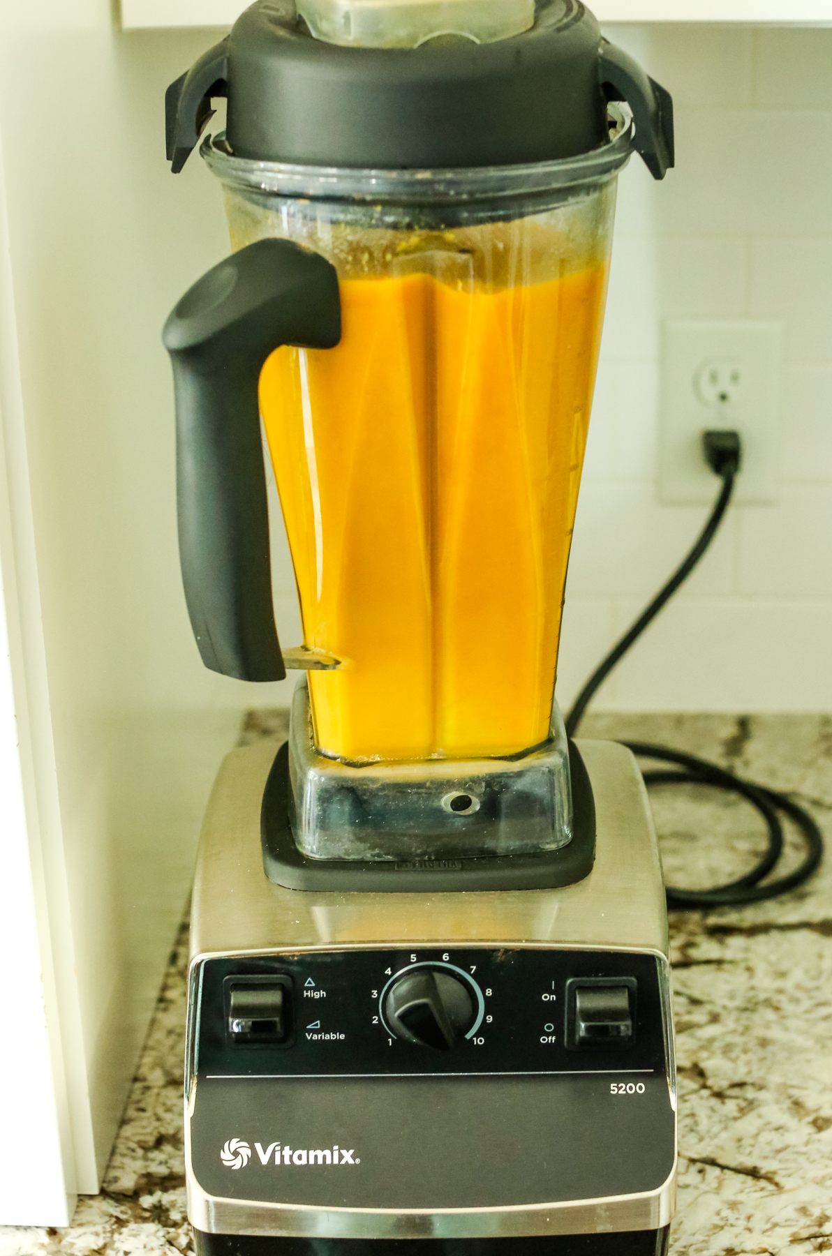 orange hued soup being blended in a vitamix blender