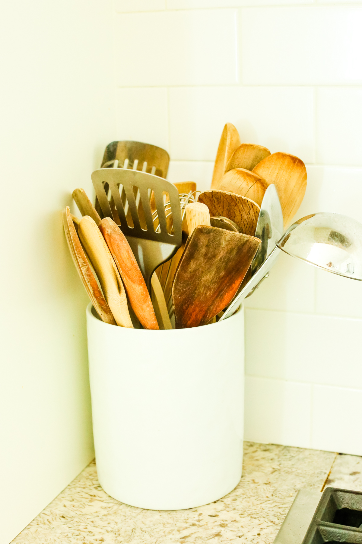 a container filled with wooden, stainless steel, and titanium cooking utensils