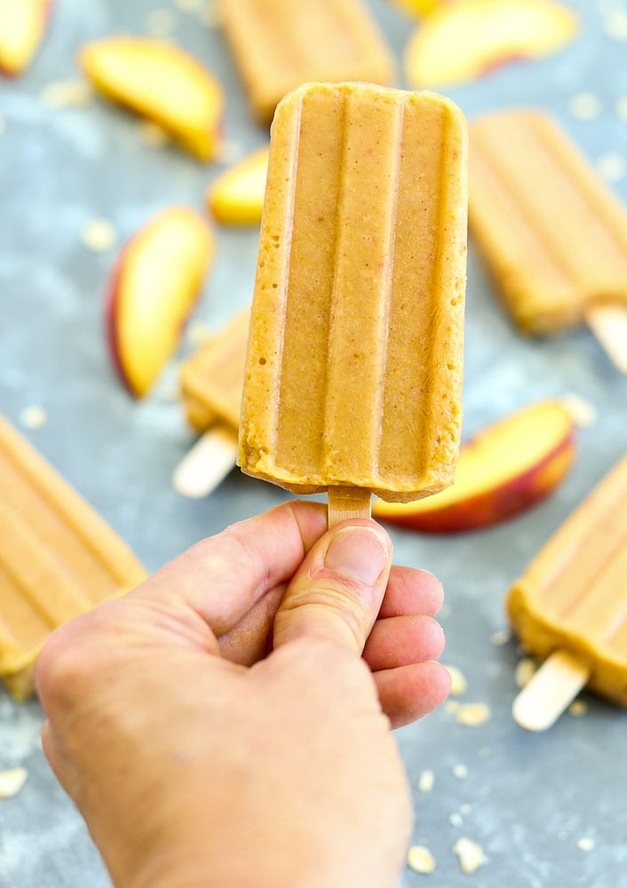 Holding a peach crisp popsicle==healthy homemade popsicle recipe #popsicle #recipe #healthy #easy #peaches #summer #kids #dessert #healthyrecipes