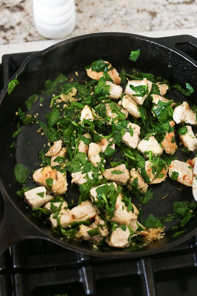 cooking the chicken and spinach in a cast iron skillet for the Mediterranean Spaghetti Squash recipe