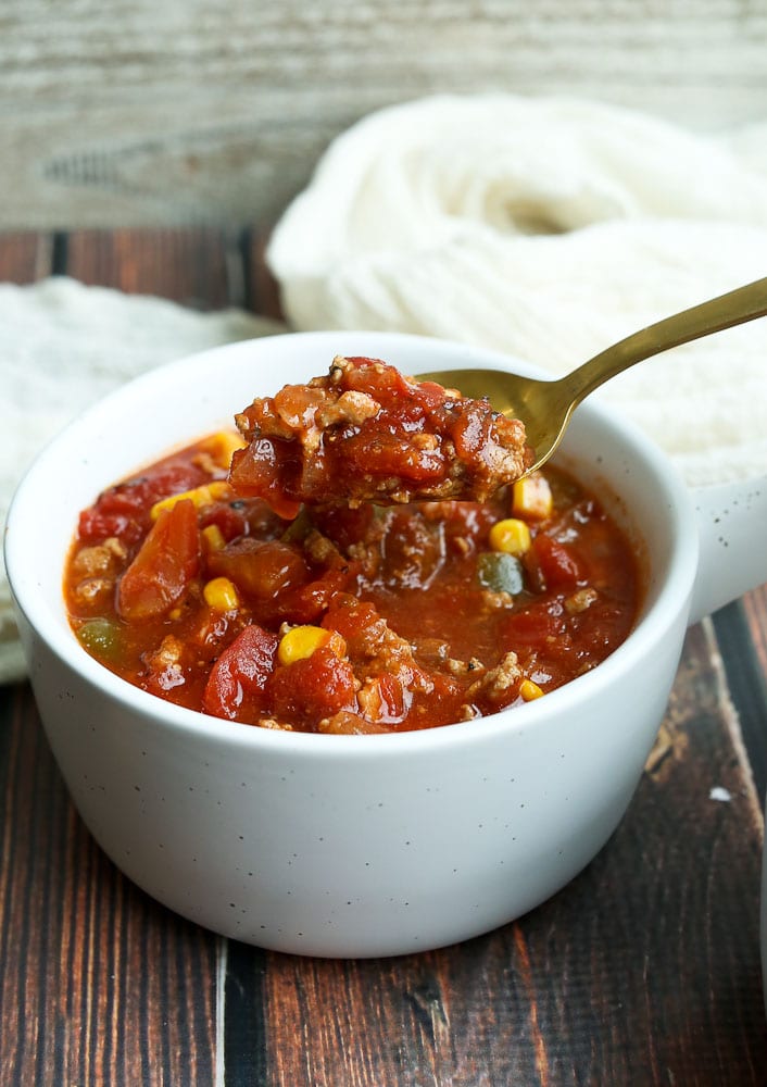 Slow Cooker Barbecue Turkey Chili Recipe in white bowl and a spoon scooping some out 