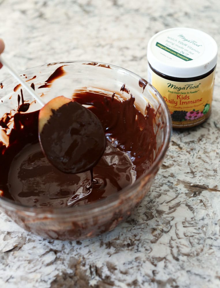 dipping the apples in chocolate for the chocolate covered apple turkey recipe