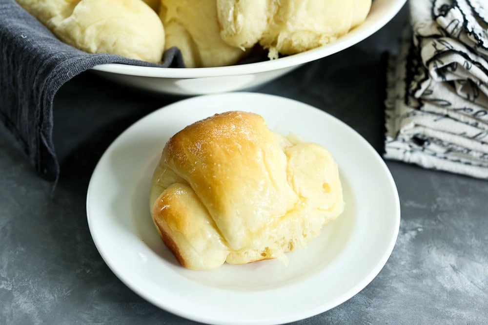 Perfect Bread Machine Dinner Rolls Recipe in a bowl with a gray napkin and on a plate