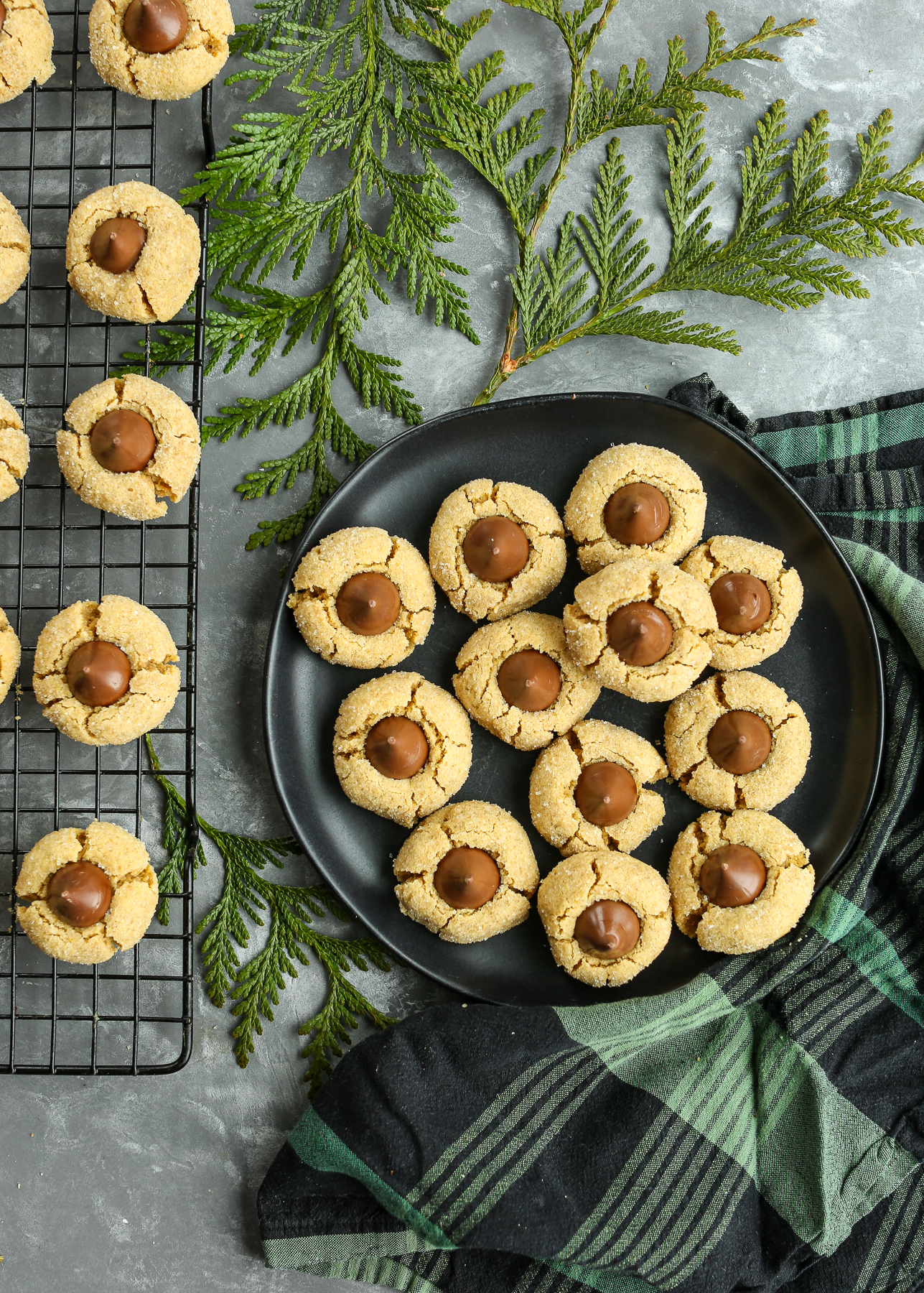 a plate of cookies with greenery on the table