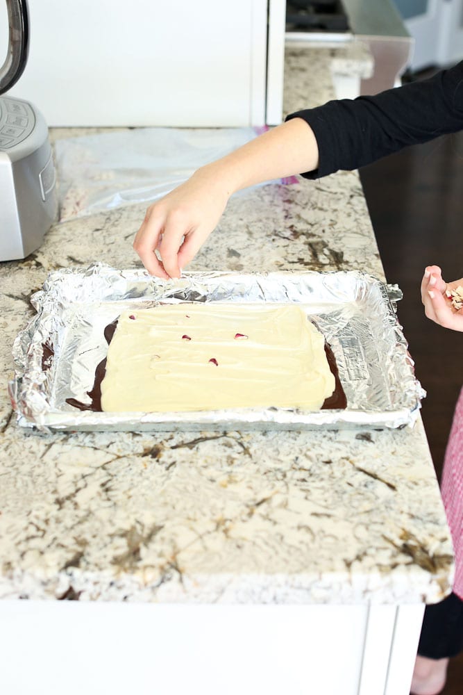 Homemade Peppermint Bark Recipe step by step instructions sprinkling the candy canes onto the white chocolate