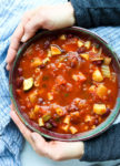 Minestrone Soup Recipe in a bowl with two hands around the bowl