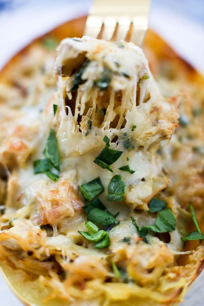 Spinach Artichoke Stuffed Spaghetti Squash with chicken recipe, taking a forkful with spaghetti squash strands and melty cheese