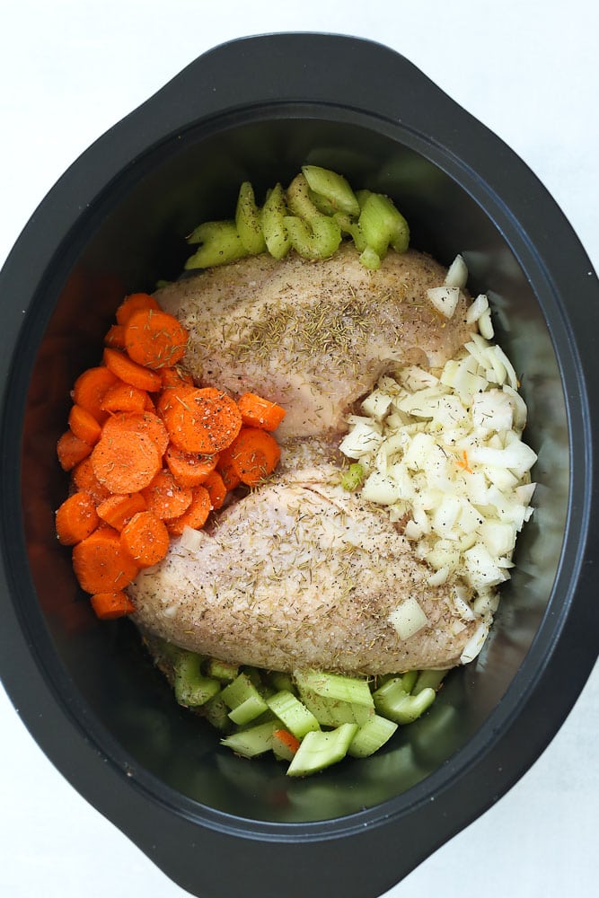 How to make easy crockpot chicken recipe, raw carrots, chicken breast, celery, and onions in the pot