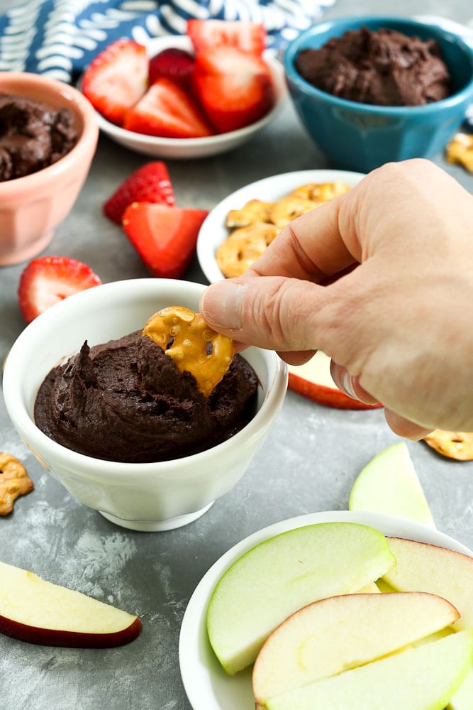 Brownie Batter Dessert Hummus recipe dipping a pretzel