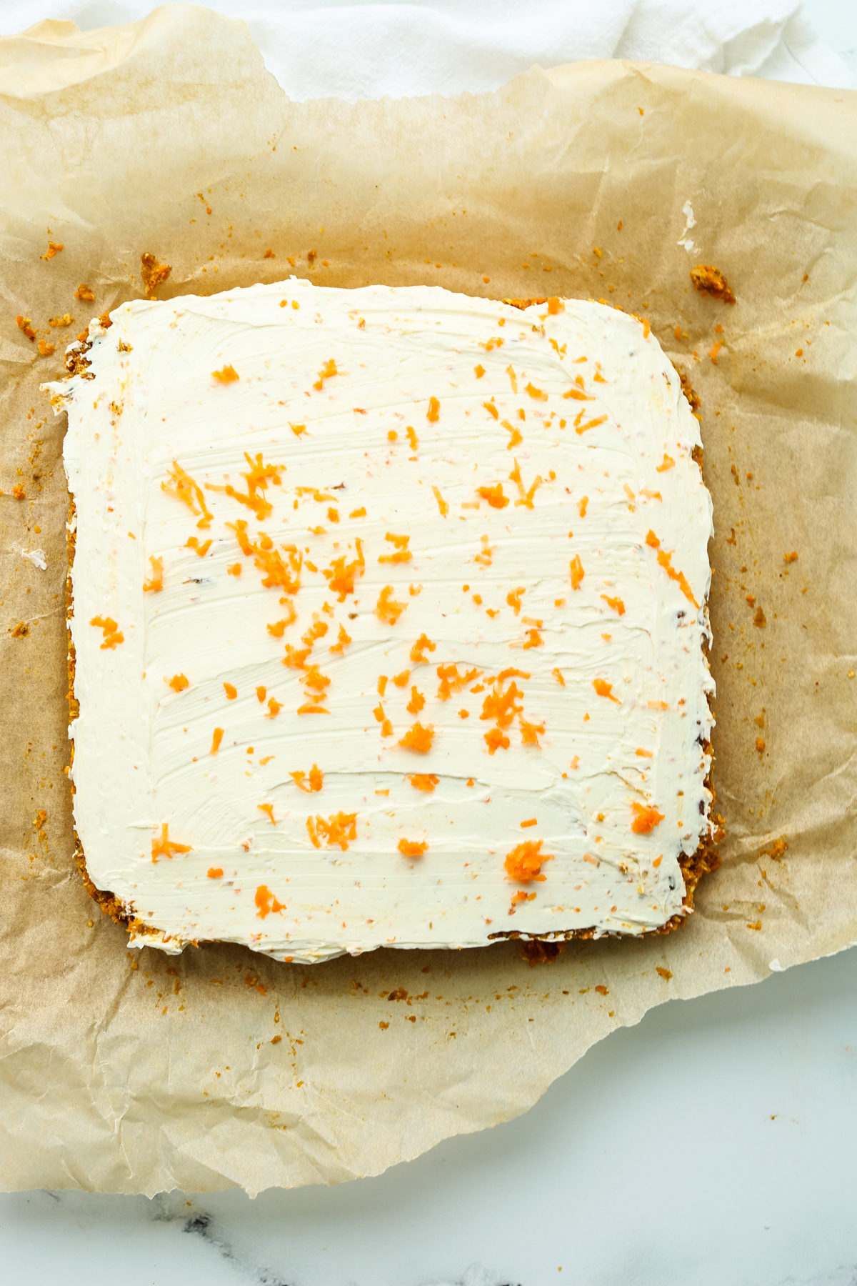 a square of healthy carrot cake bars with grated carrot on top before cutting