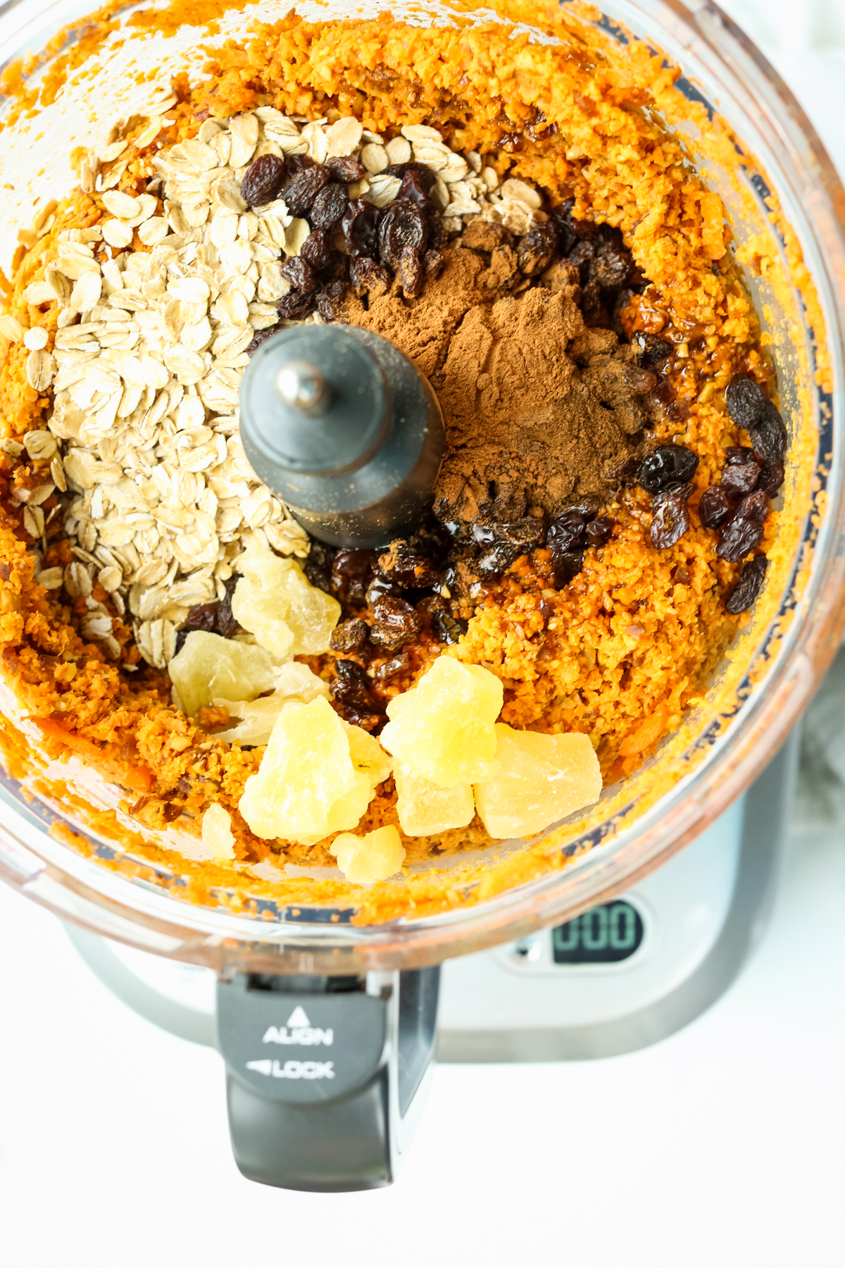 an orange mixture with dried pineapple, raisins, and oats in a food processor 