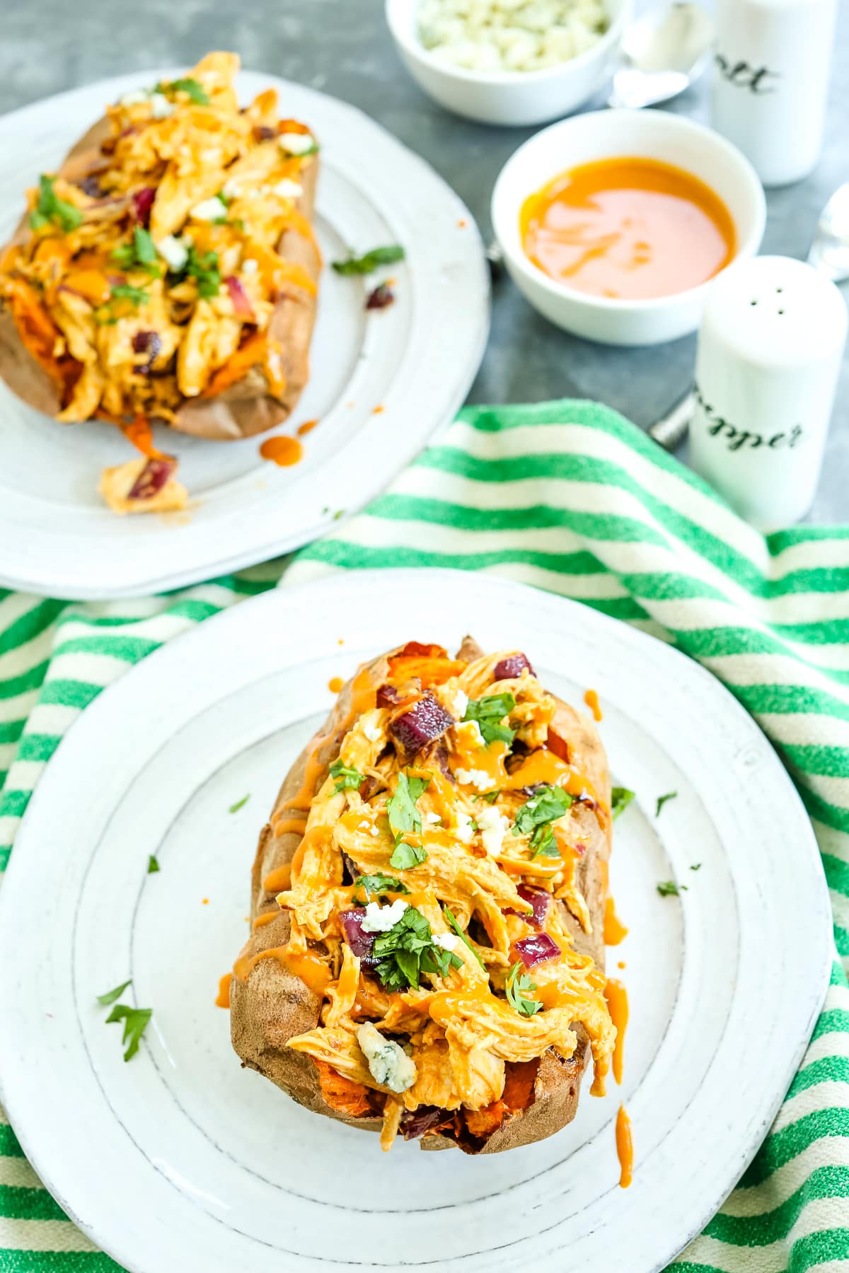 buffalo chicken stuffed sweet potatoes on a dinner table with a green and white striped napkin