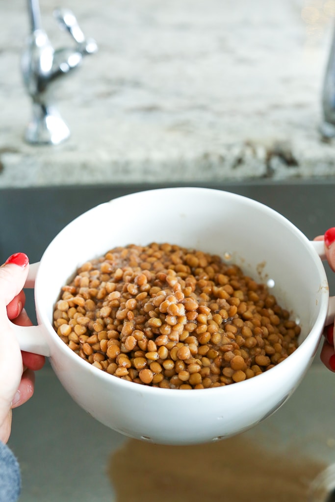 lentils in a white colander being drained over the sink
