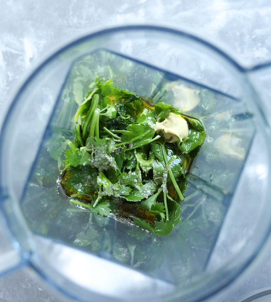 fresh parsley and other ingredients for dressing in a blender, an overhead view