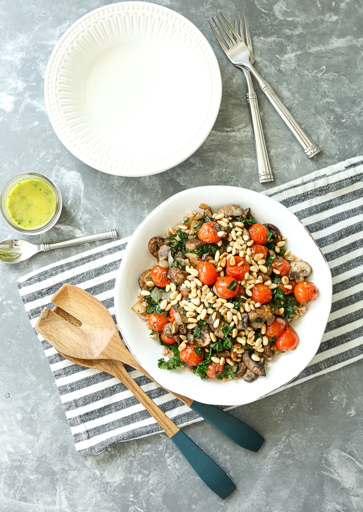 overhead shot of one full bowl and an empty bowl, serving spoons, and a jar of the dressing