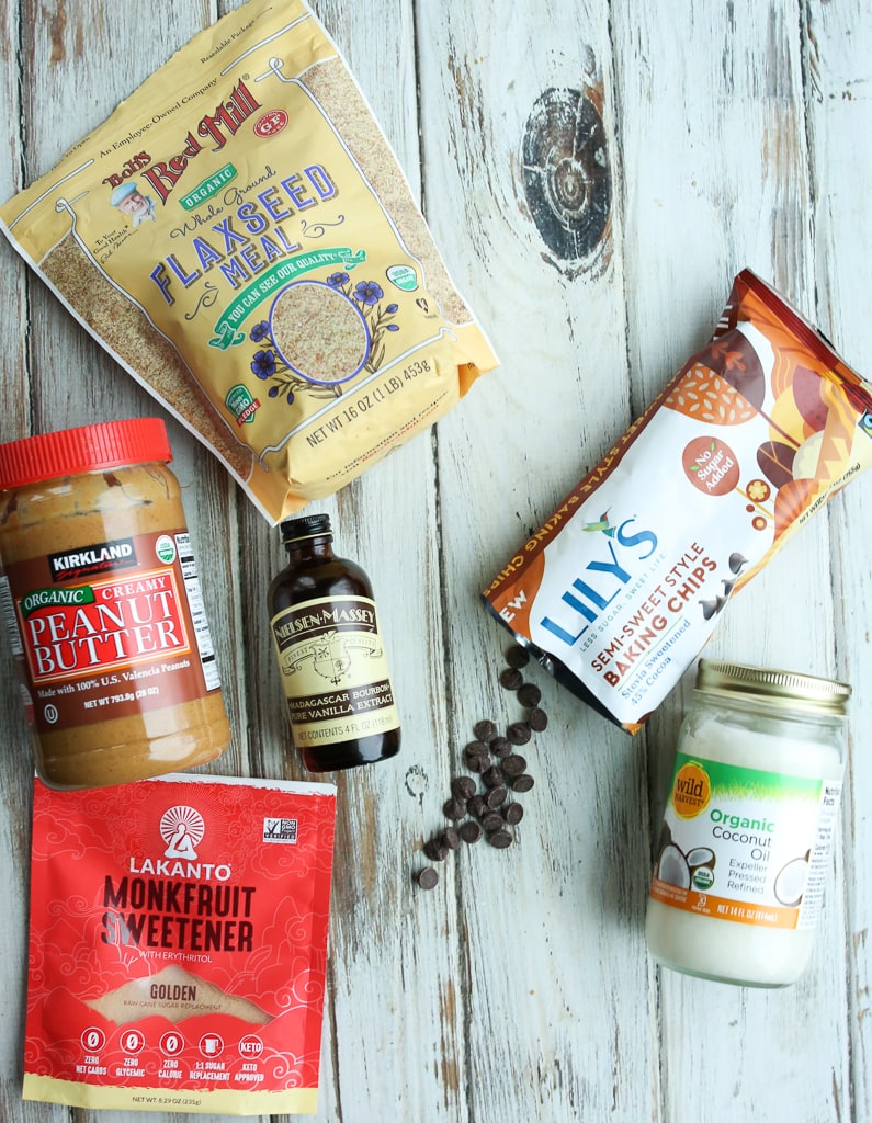 overhead shot of ingredients: ground flaxseed meal, peanut butter, vanilla extract, monk fruit sweetener, Lily's chocolate chips, and coconut oil
