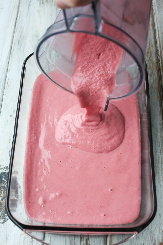 pouring a pink thick liquid from a blender to a glass pan