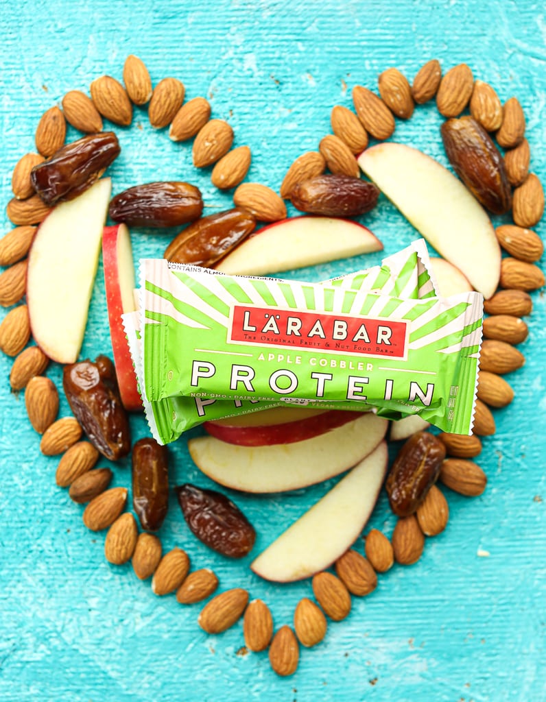 Almonds in the shape of a heart with dates, apples, and Larabar protein bars inside the heart