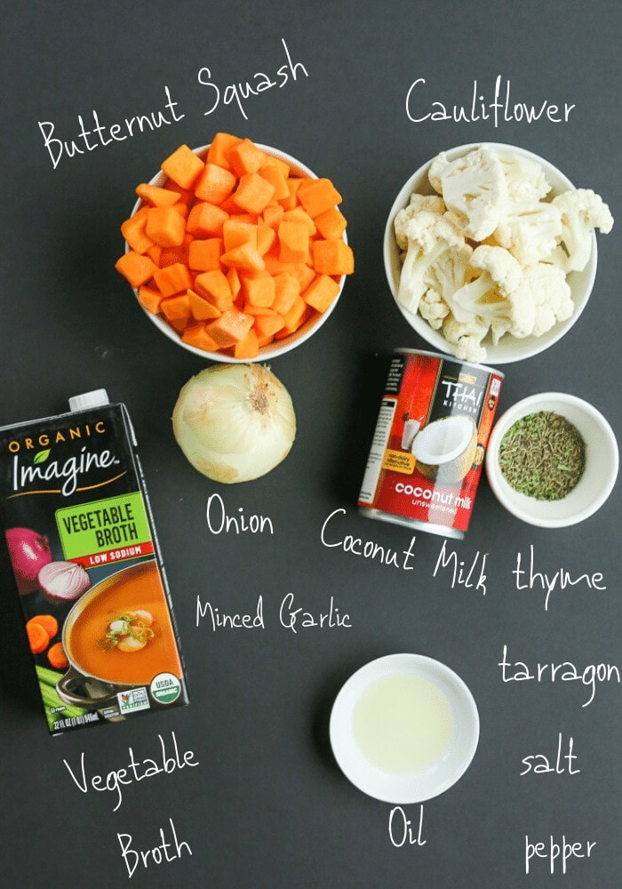 all ingredients on a black board labeled with white writing: chopped butternut squash, chopped cauliflower, onion, can of coconut milk, spices, oil, and a box of vegetable broth