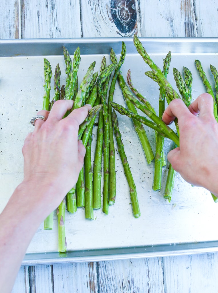 a tray of baked asparagus with melted parmesan cheese and lemon zest