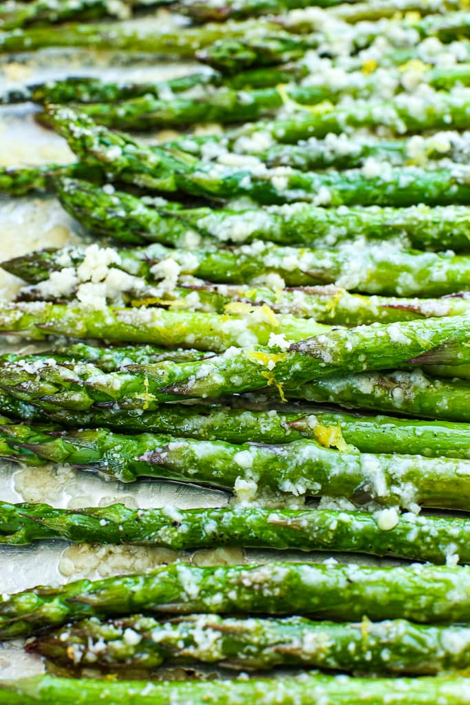 close up picture of baked asparagus that's been roasted with parmesan cheese and topped with lemon zest