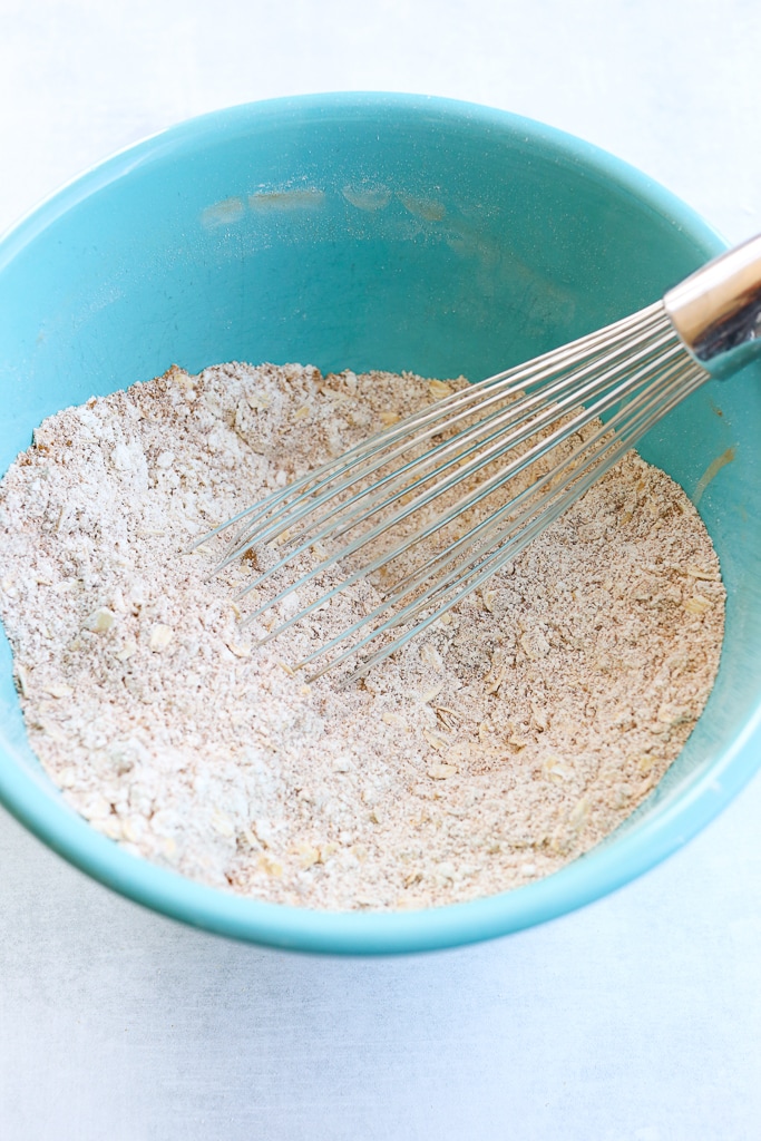 dry ingredients of morning glory muffins in a turquoise bowl with a whisk
